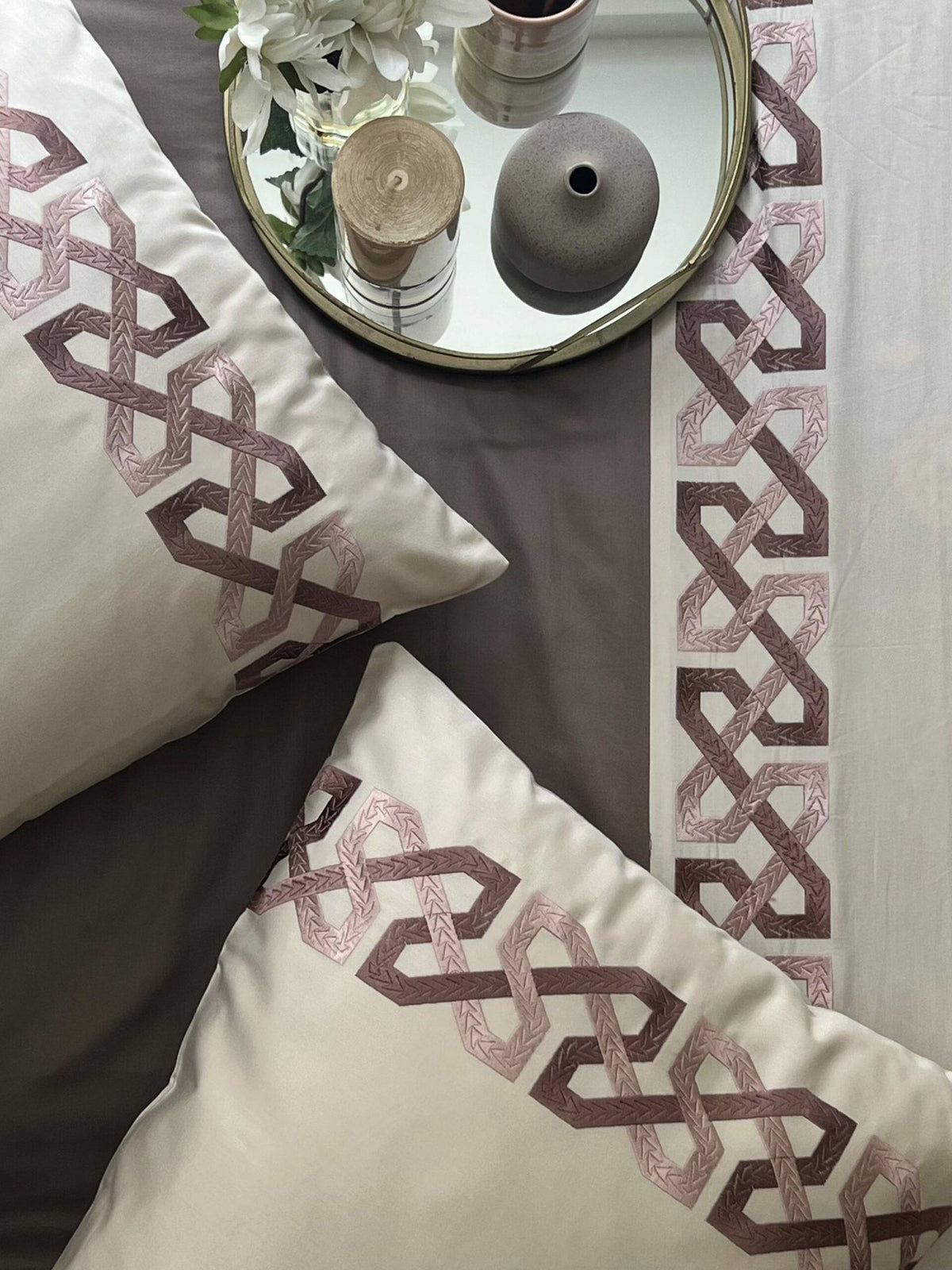 Oats beige bedding with a brown and pink interlocking geometric embroidered border