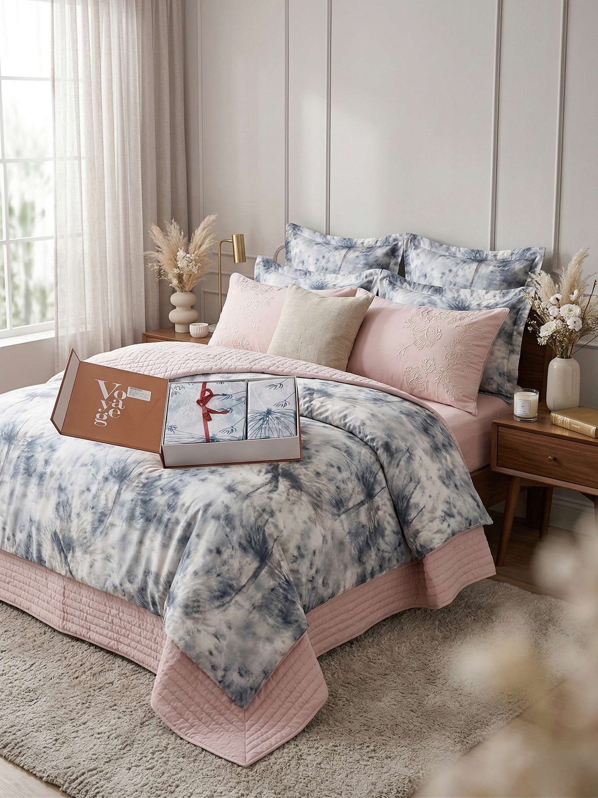 Bed dressed in a blue and white tie-dye bedsheet with a blush quilted border