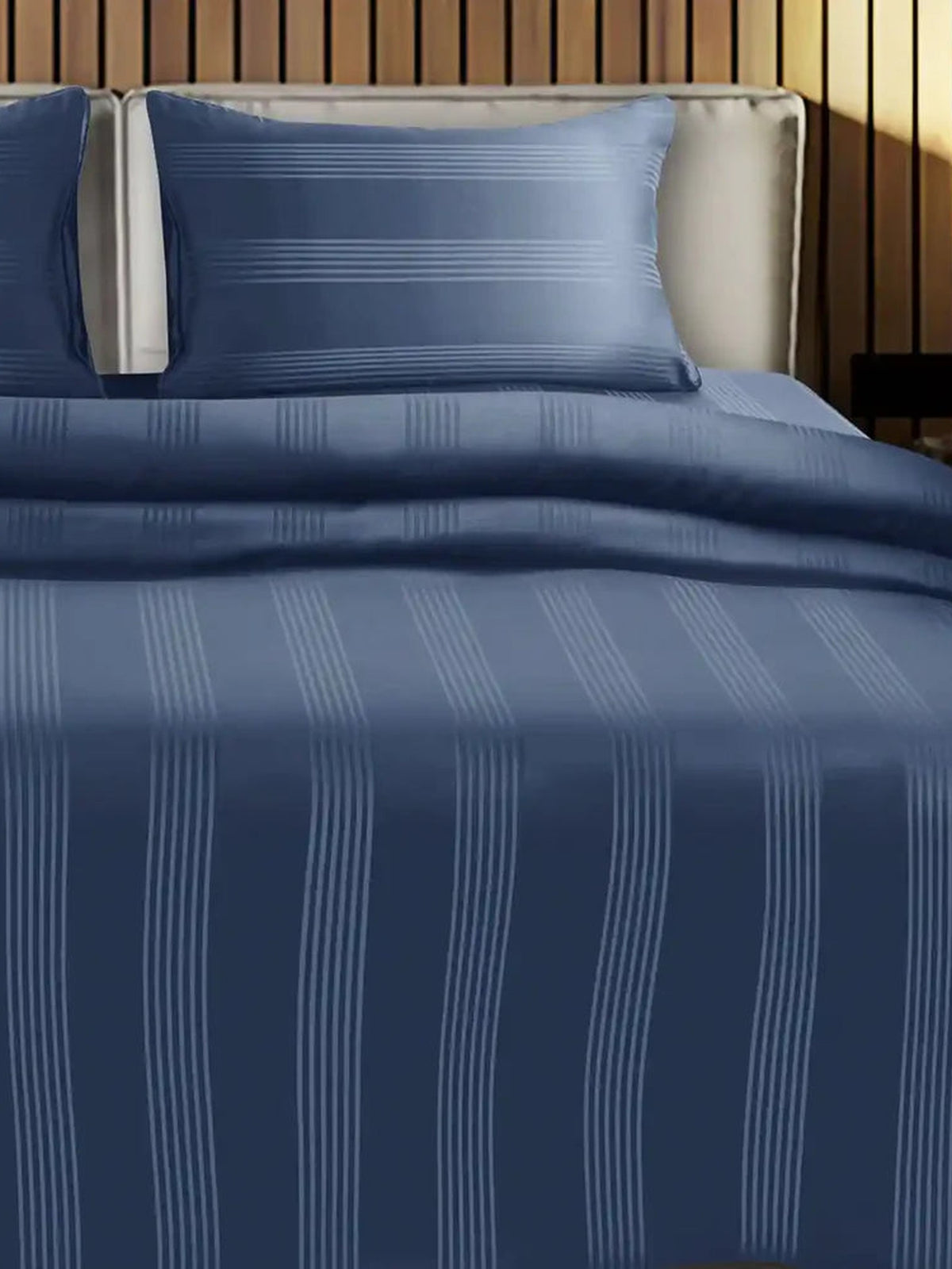 Denim blue satin stripe cotton bedsheet on a made bed with matching pillow cover