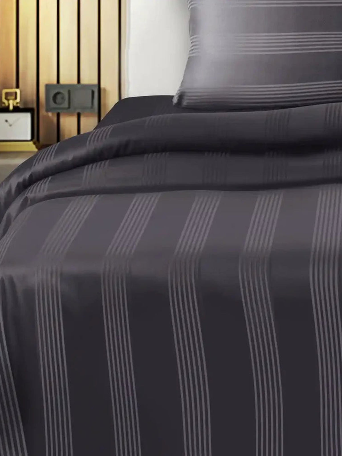 Charcoal grey satin stripe cotton bedsheet on a made bed with matching pillow