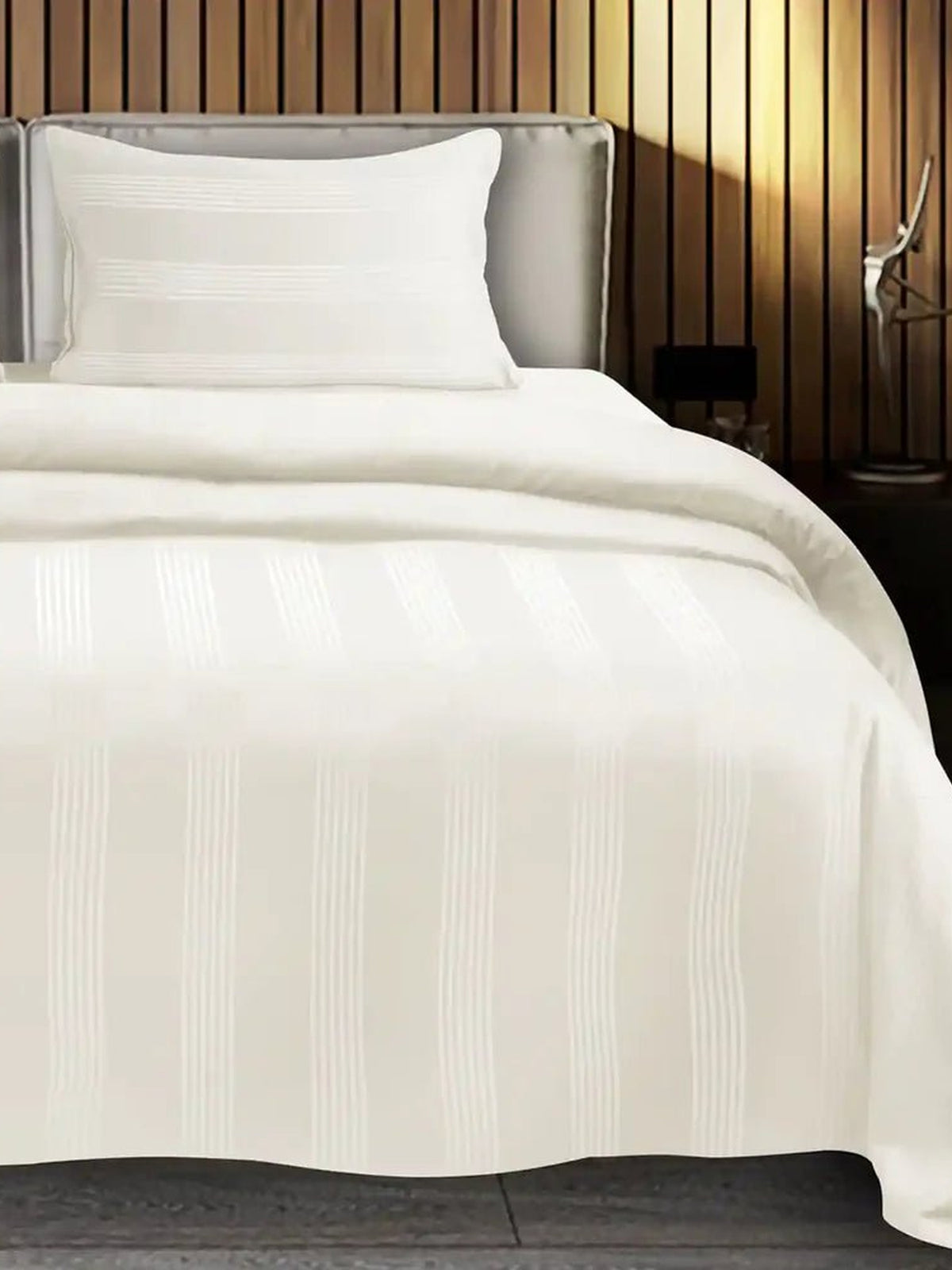 Ivory satin stripe cotton bedsheet on a made bed with matching pillow