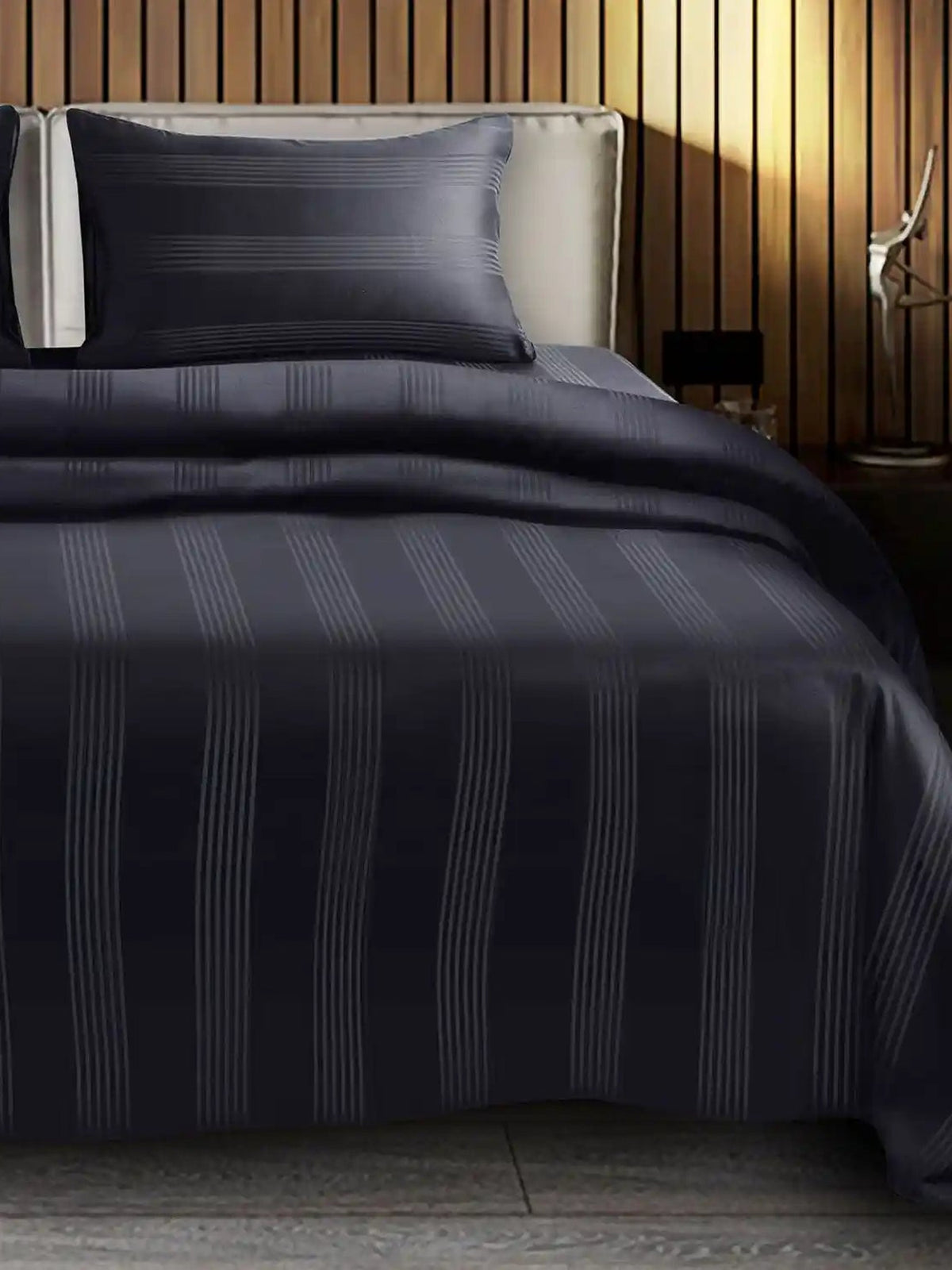 Black satin stripe cotton bedsheet on a made bed with matching pillow