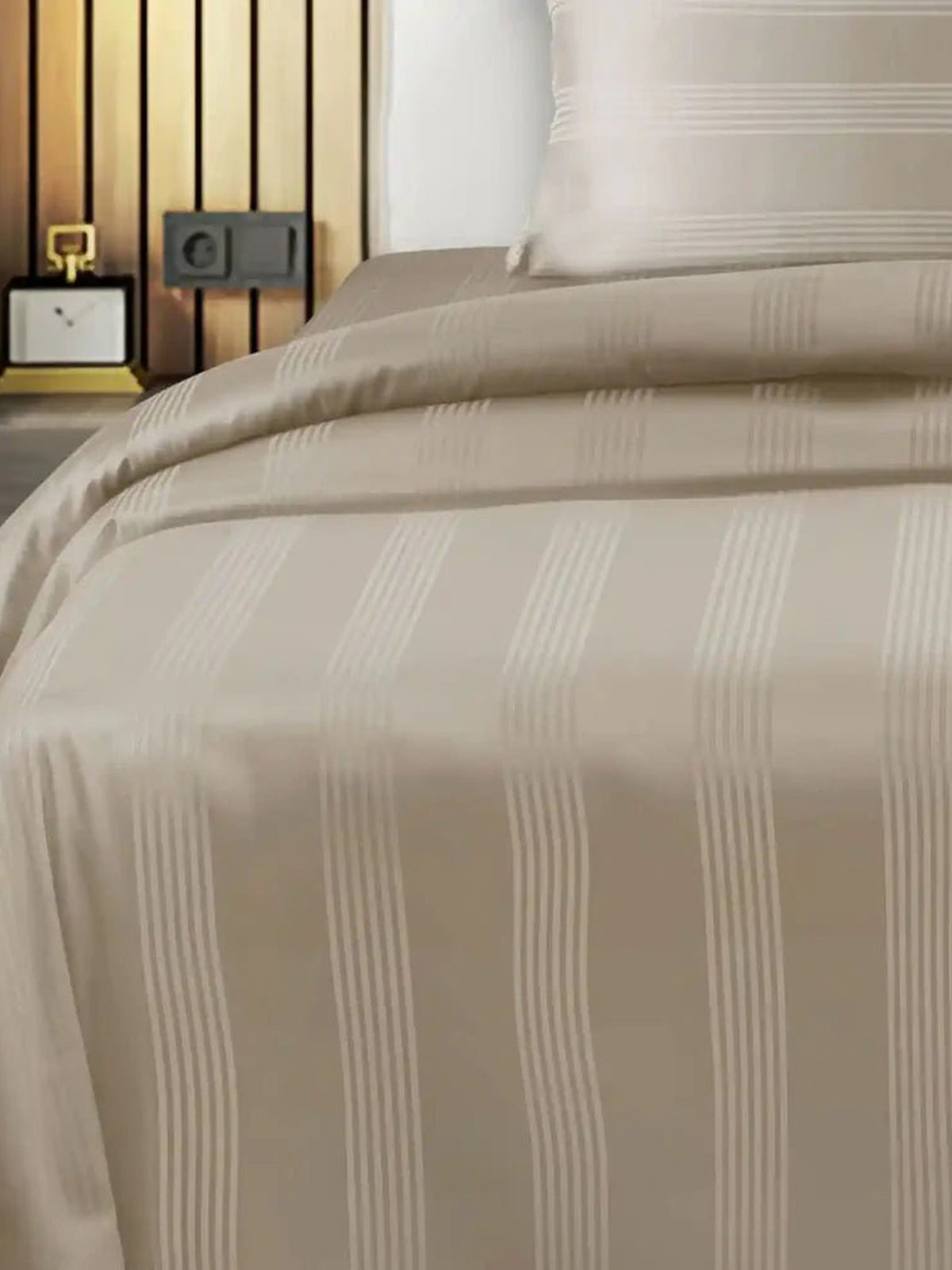 Pale greige satin stripe cotton bedsheet draped over a bed with matching pillow