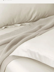 Ivory Supima cotton bedding with a waffle throw folded across it
