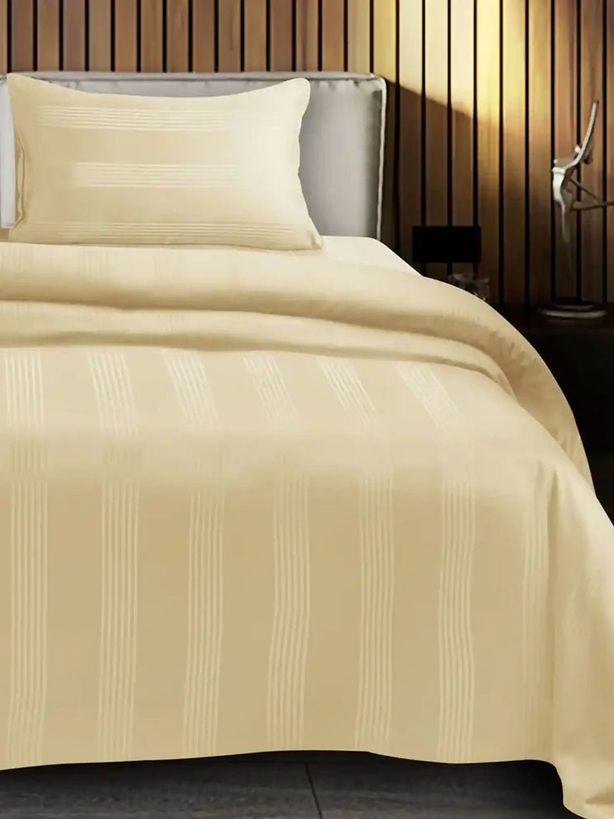 Pale butter cream satin stripe cotton bedsheet on a made bed with matching pillow