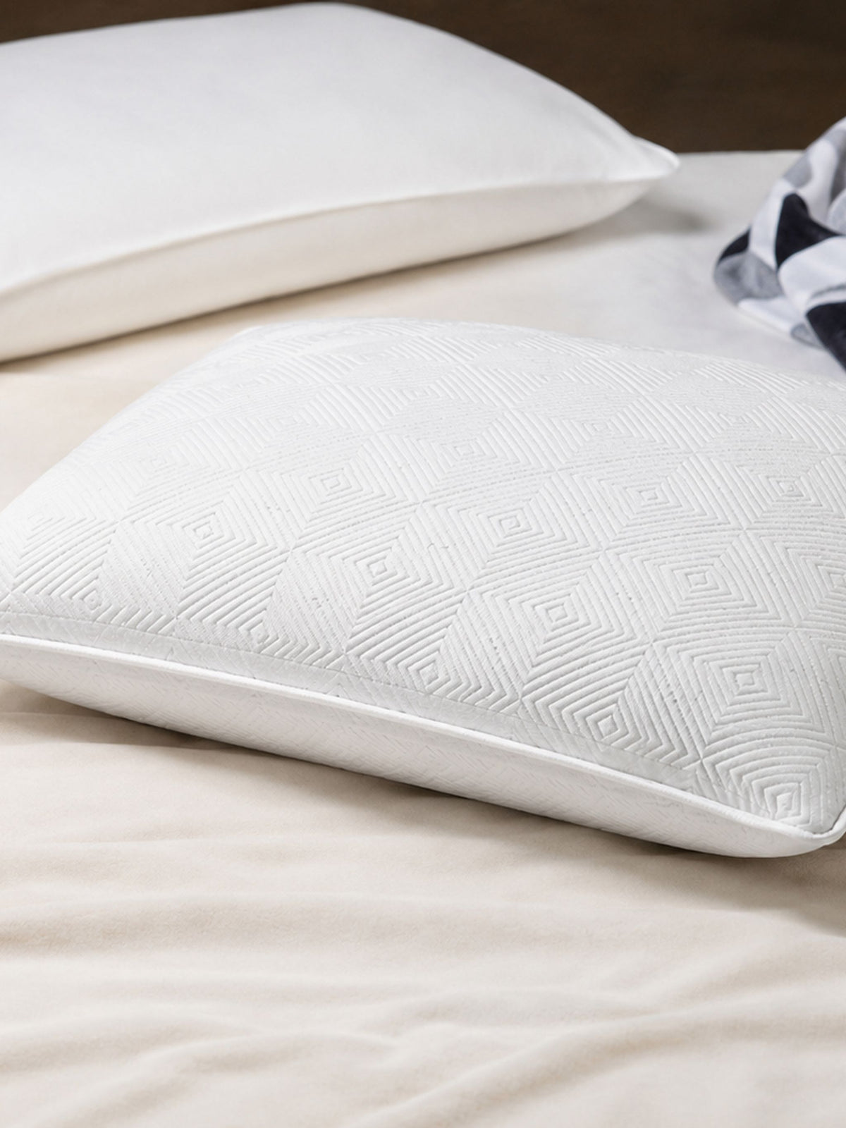 Two plain white latex pillows on white bedding