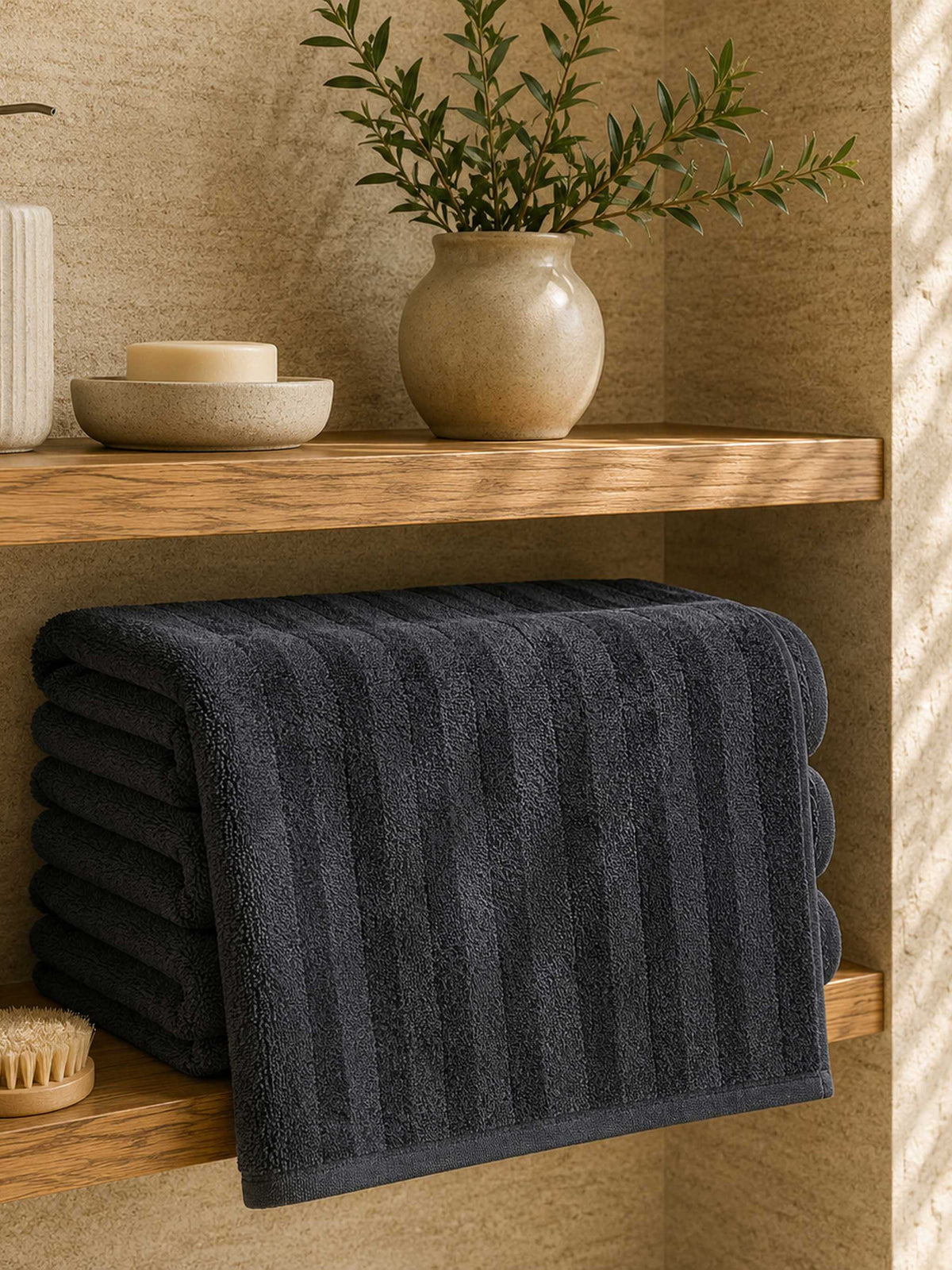 Charcoal ribbed cotton towels folded on a wooden bathroom shelf