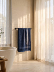 Navy blue cotton bath towel with chevron woven border displayed in a modern bathroom
