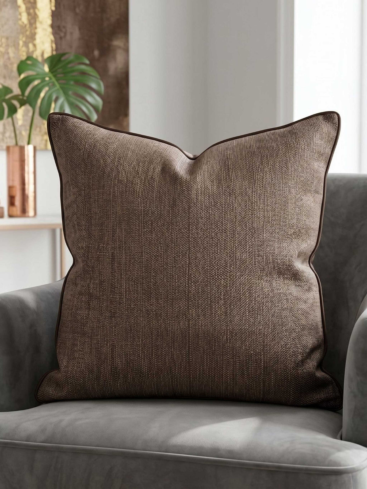 Textured brown woven cushion cover with piped edge on a grey armchair