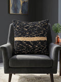 Black textured woven cushion cover with beige geometric detailing placed on a modern armchair