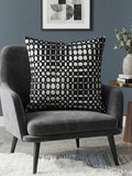 Black velvet cushion cover with geometric woven circular pattern in contrasting ivory tones