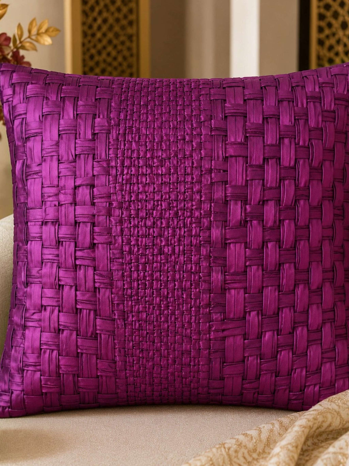 Purple woven pillow on a beige couch with decorative elements.