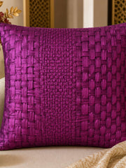 Purple woven pillow on a beige couch with decorative elements.