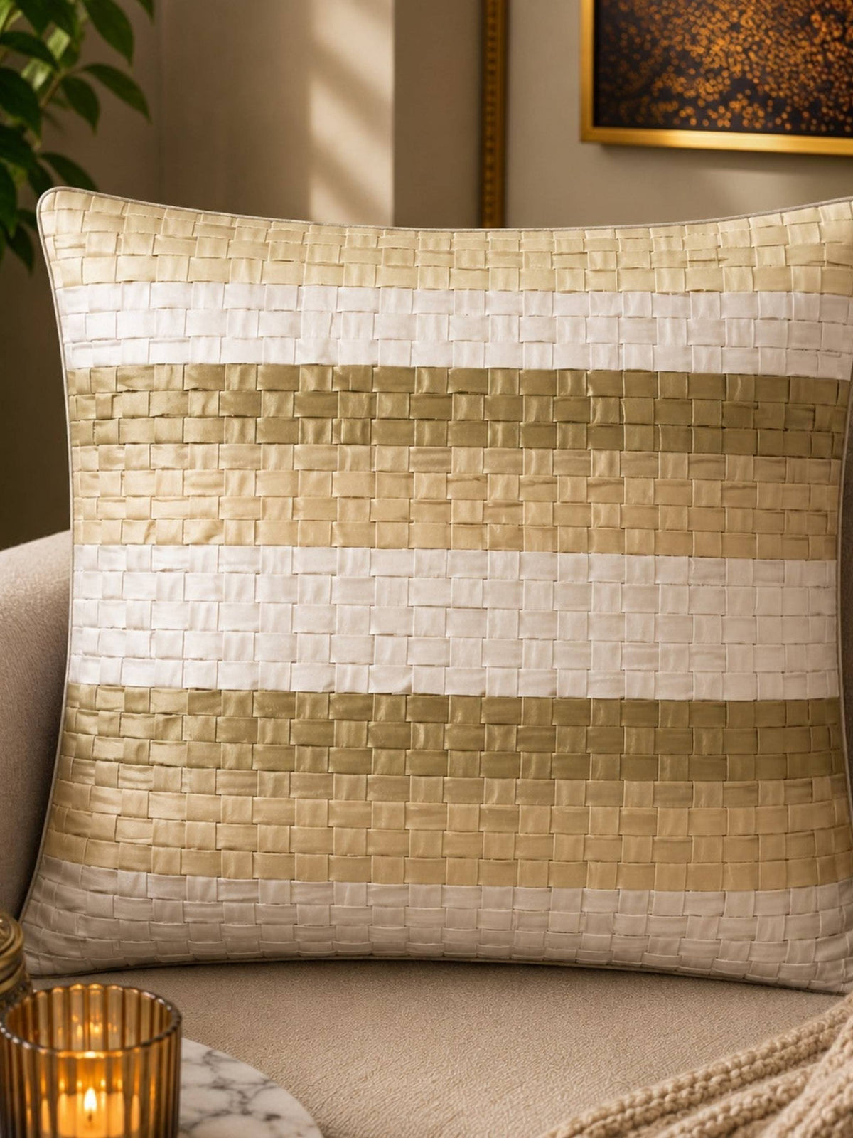 Jagdish Store decorative woven cushion cover in cream and gold with a subtle striped texture on a soft rug.