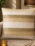 Jagdish Store decorative woven cushion cover in cream and gold with a subtle striped texture on a soft rug.