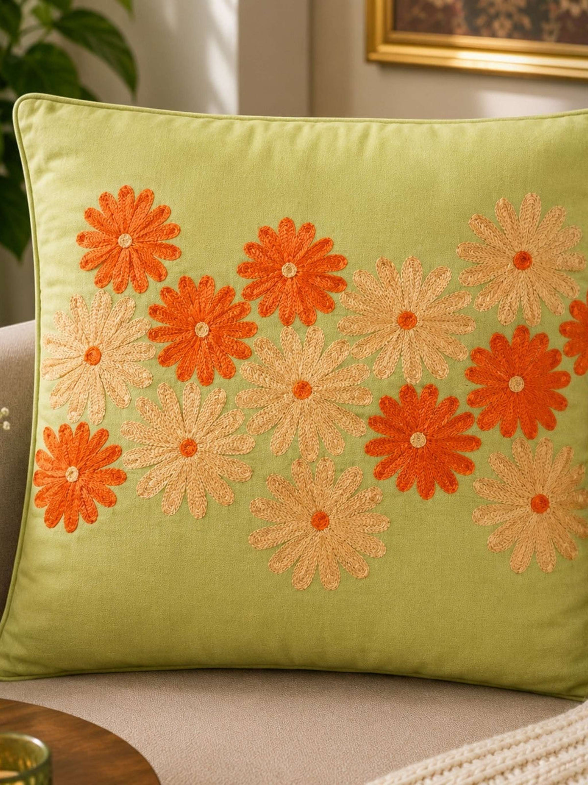 Jagdish Store lime green cushion cover with embroidered orange and gold floral pattern. Textured fabric.