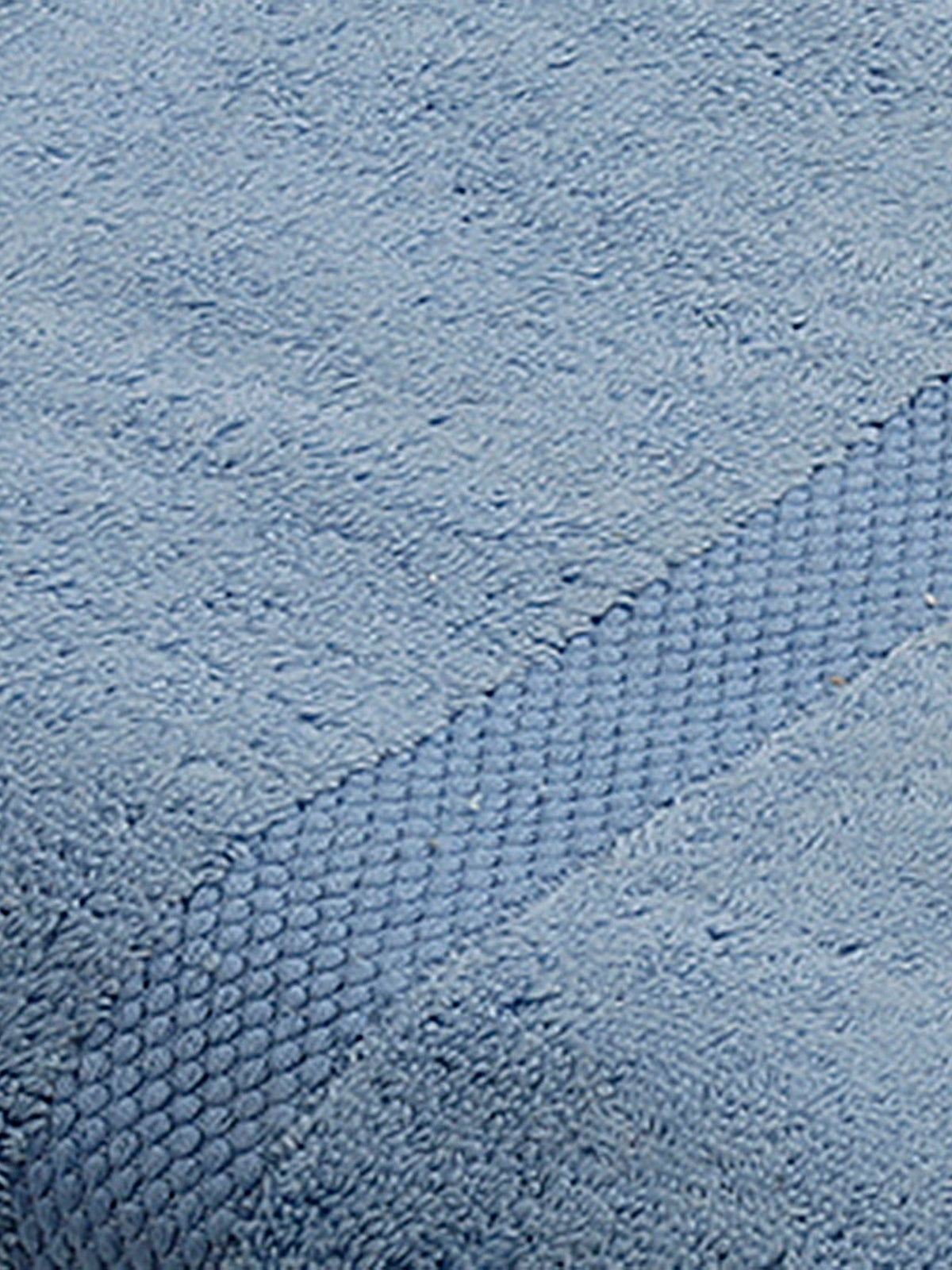 Close-up of light blue cotton bath towel folded, showing the honeycomb woven border texture