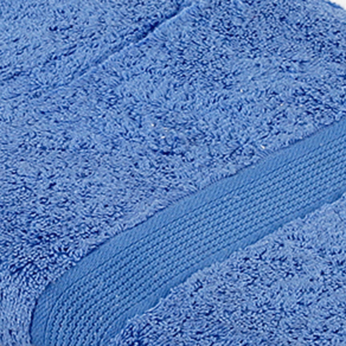 Close-up of cornflower-blue cotton bath towel folded, showing the ribbed woven border texture