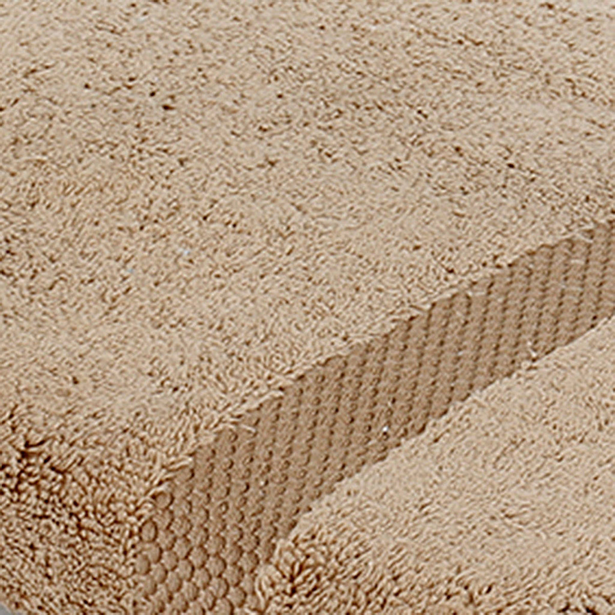 Close-up of sand-beige cotton bath towel folded, showing the honeycomb woven border texture