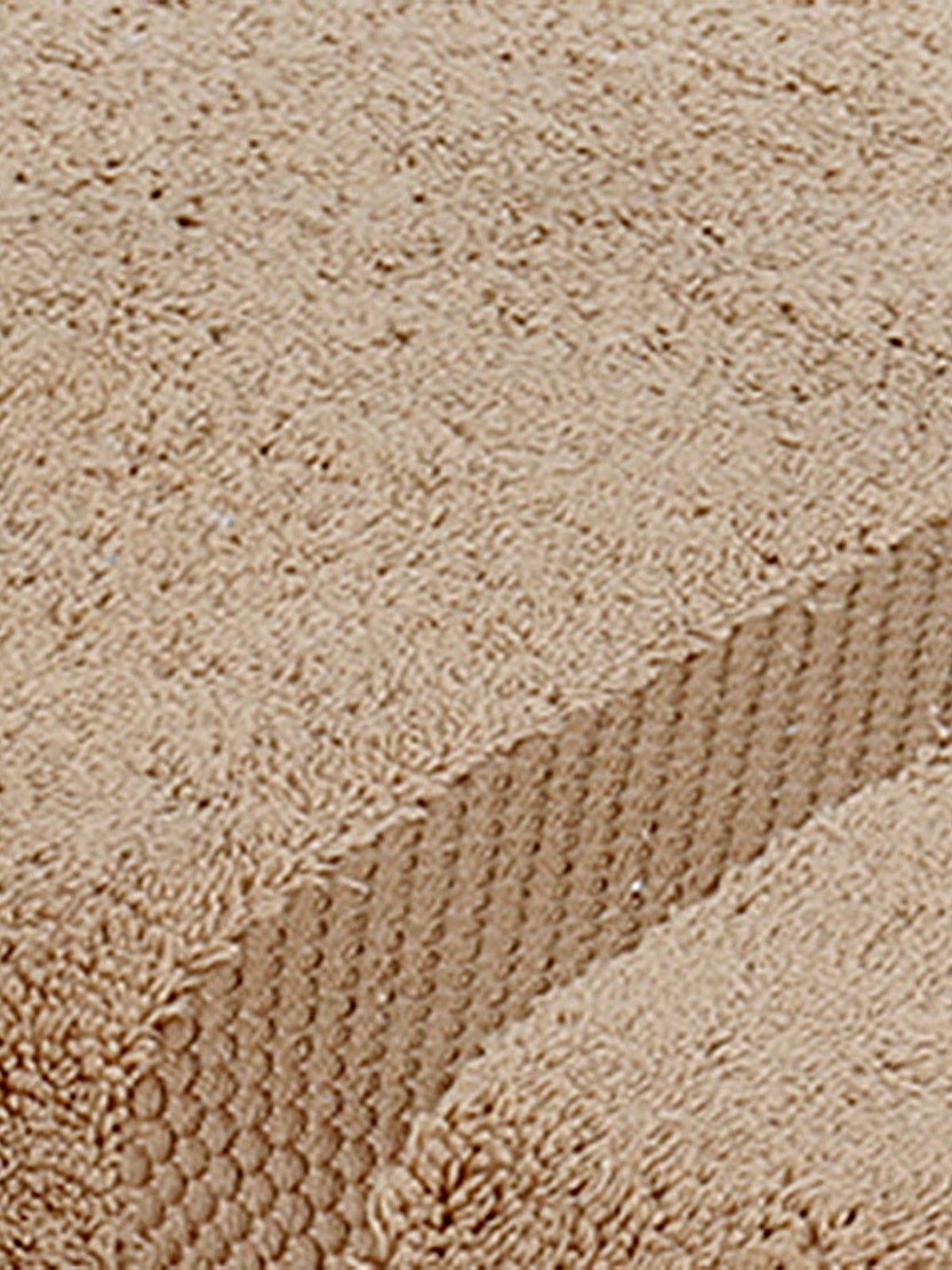 Close-up of sand-beige cotton bath towel folded, showing the honeycomb woven border texture