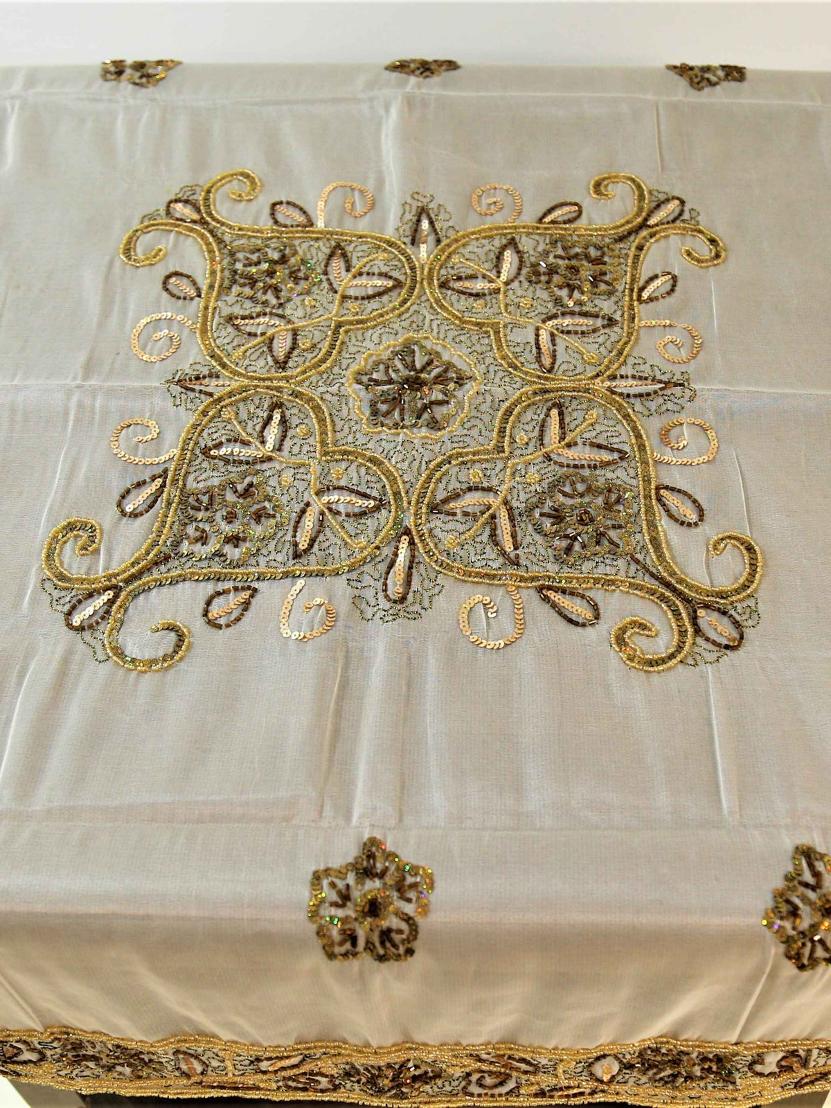 Off-white organza table cover with a gold-beaded floral medallion embroidered at the centre and a scalloped gold-beaded lace border