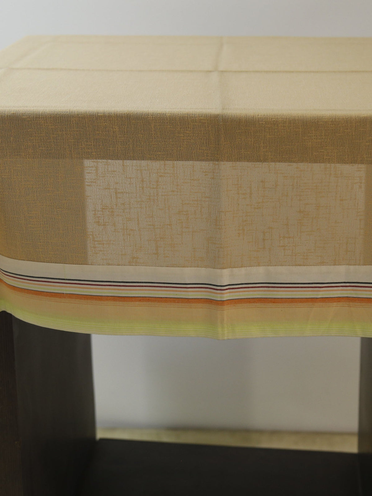 Solid beige linen table cover with a multicolour striped trim along the edge