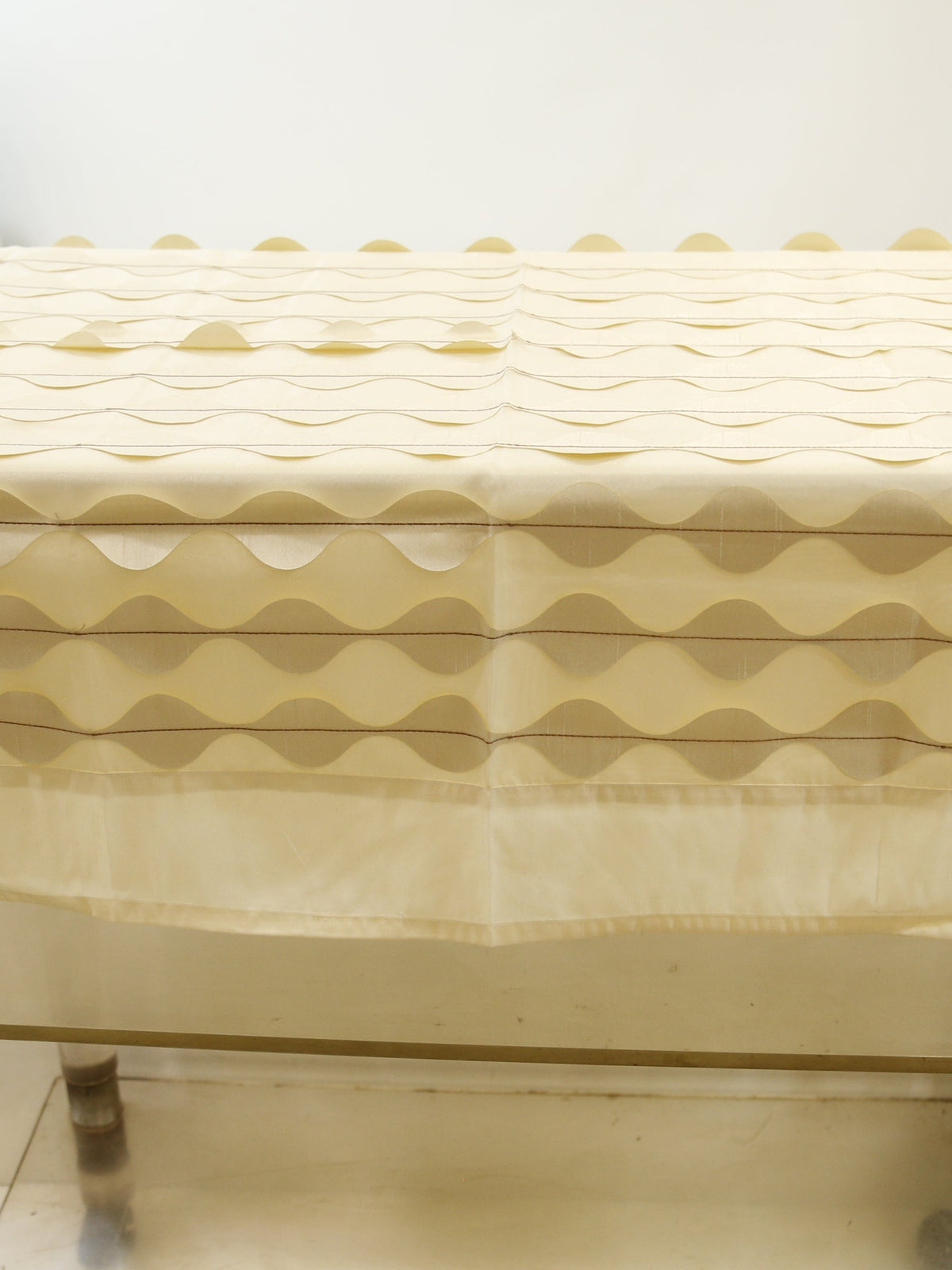 Cream table cover with a wavy ripple-appliqué stripe pattern and a scalloped hem