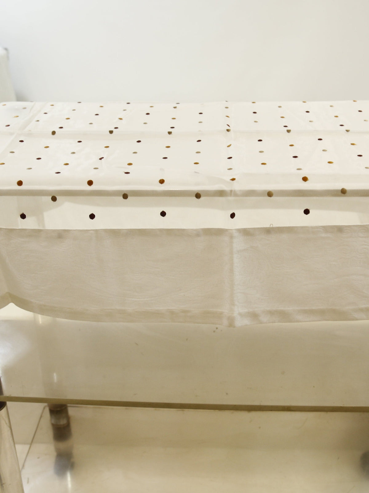 White sheer table cover with scattered multicolour bead dots over a jacquard paisley weave, with a scalloped hem