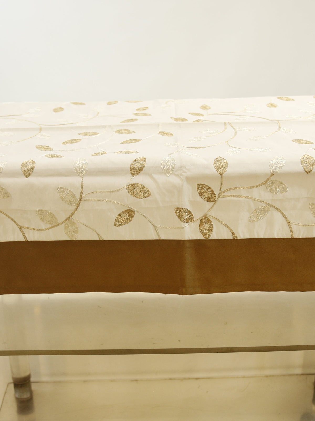 Cream table cover with a gold embroidered leaf-and-vine pattern and a solid brown border
