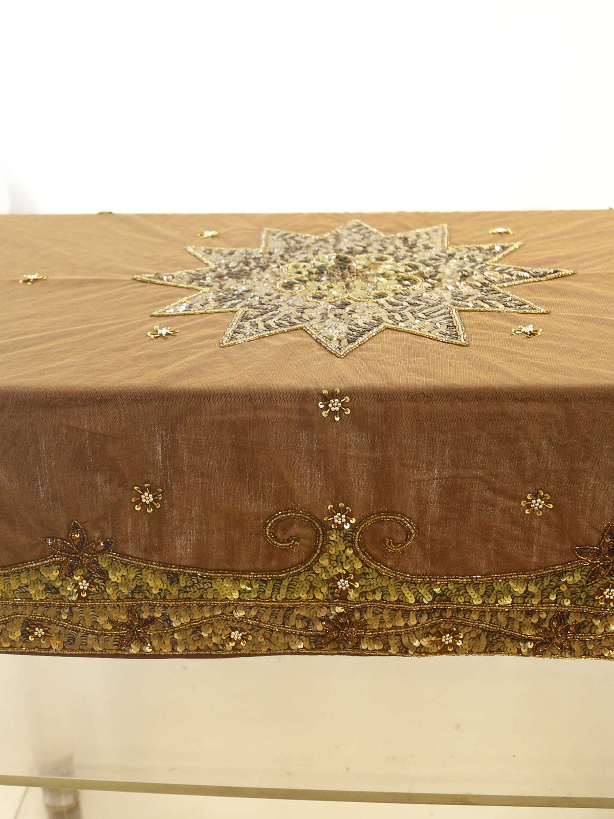 Brown velvet table cover with a silver sequinned star medallion at the centre and a gold-green sequinned scalloped border