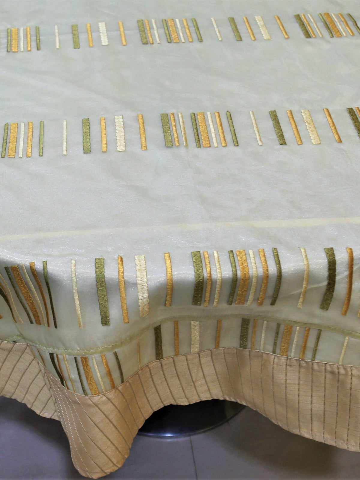 Round pale gold table cover with embroidered multicolour vertical dash stripes and a tan striped border