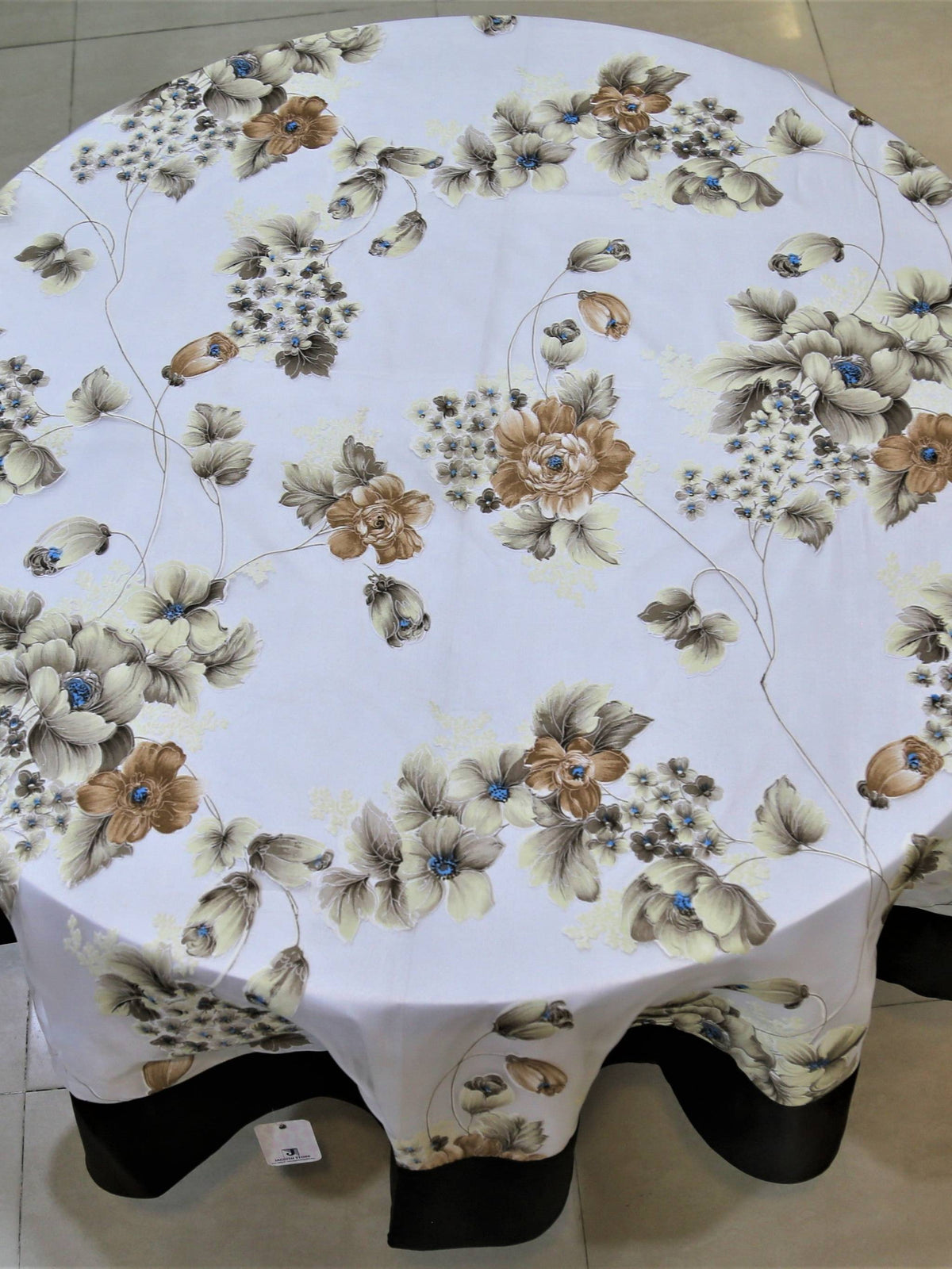 Round white table cover with a printed beige-brown floral bouquet pattern and a solid black underskirt