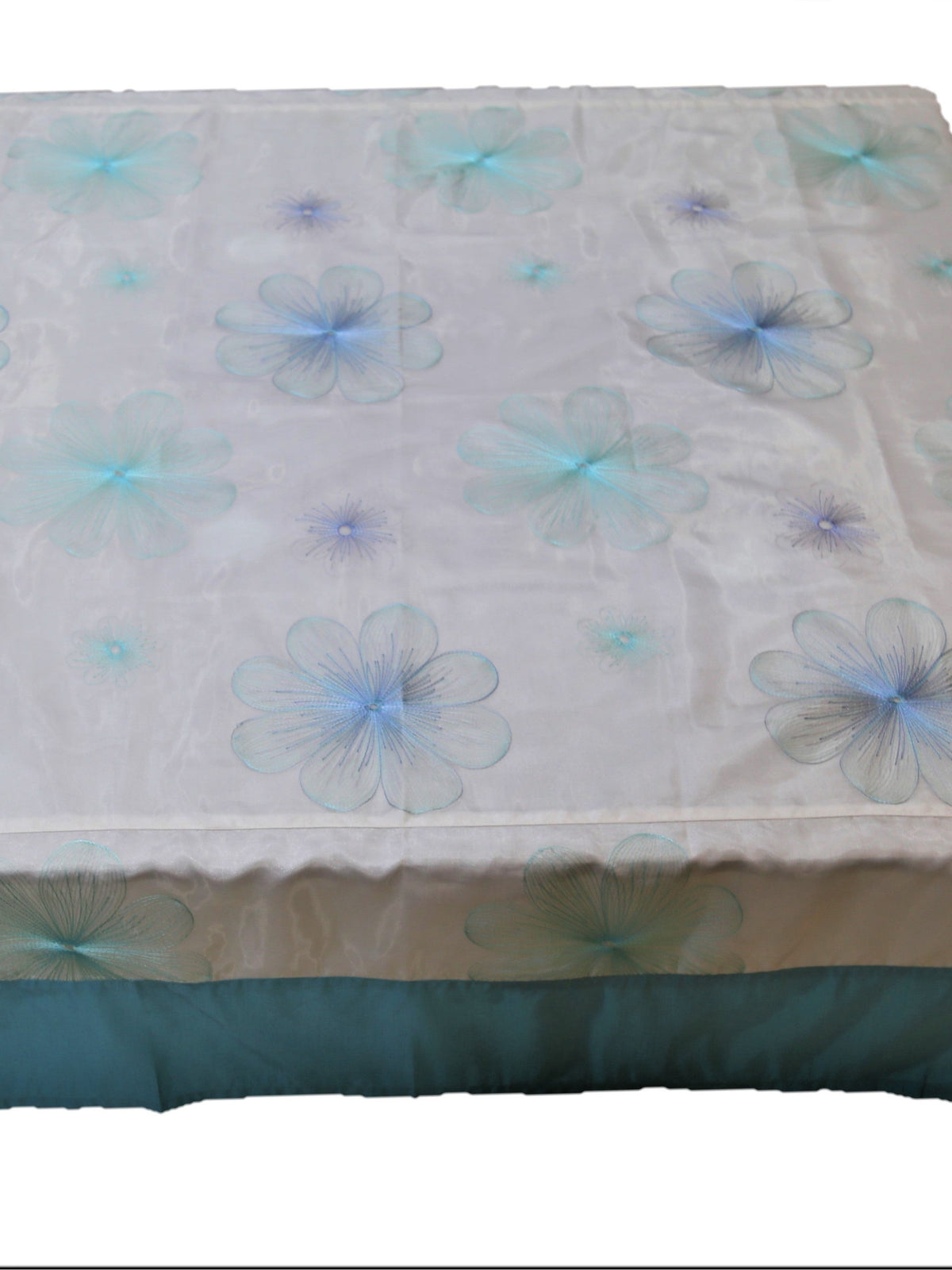 White table cover with a pale blue embroidered flower pattern and a solid teal-blue underskirt