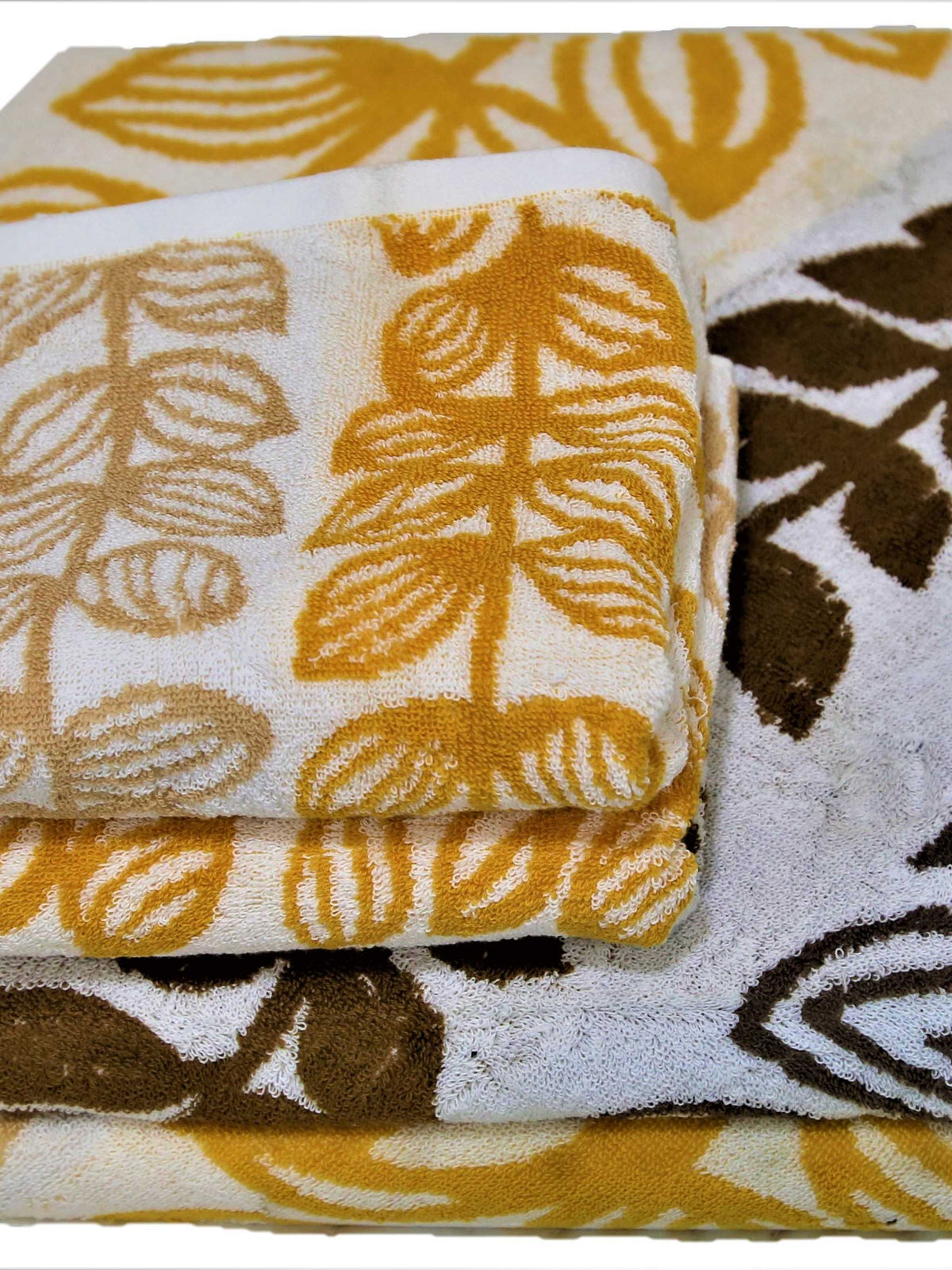White cotton towel set with a gold and brown leaf-print stripe pattern