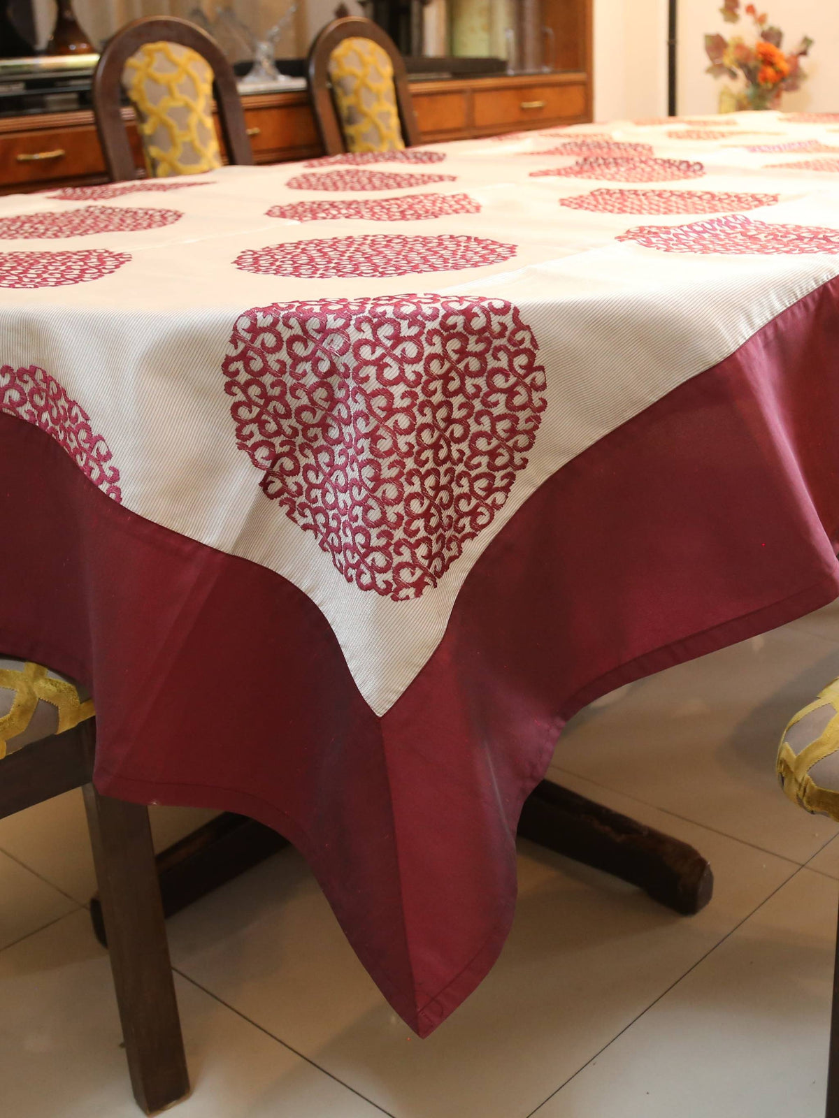 White oval table cover with a maroon circular medallion print and a solid maroon border