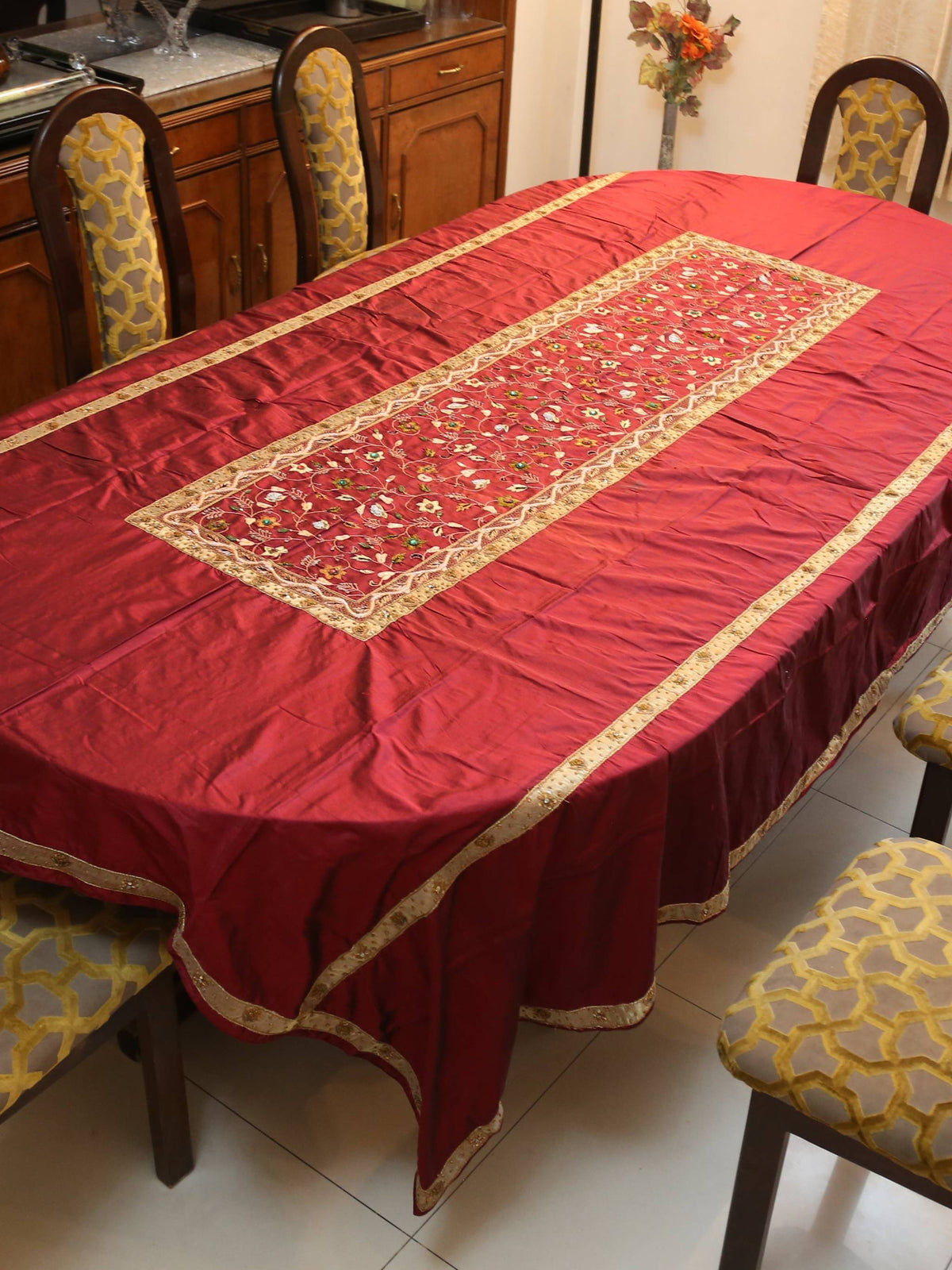 Maroon silk table cover with a gold-bordered floral embroidered runner panel down the centre