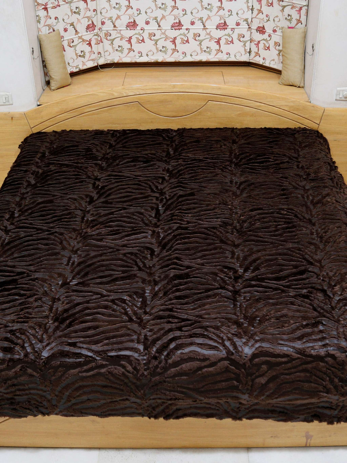 Dark chocolate-brown faux-fur blanket with a wavy zebra-stripe texture, spread flat over a bed