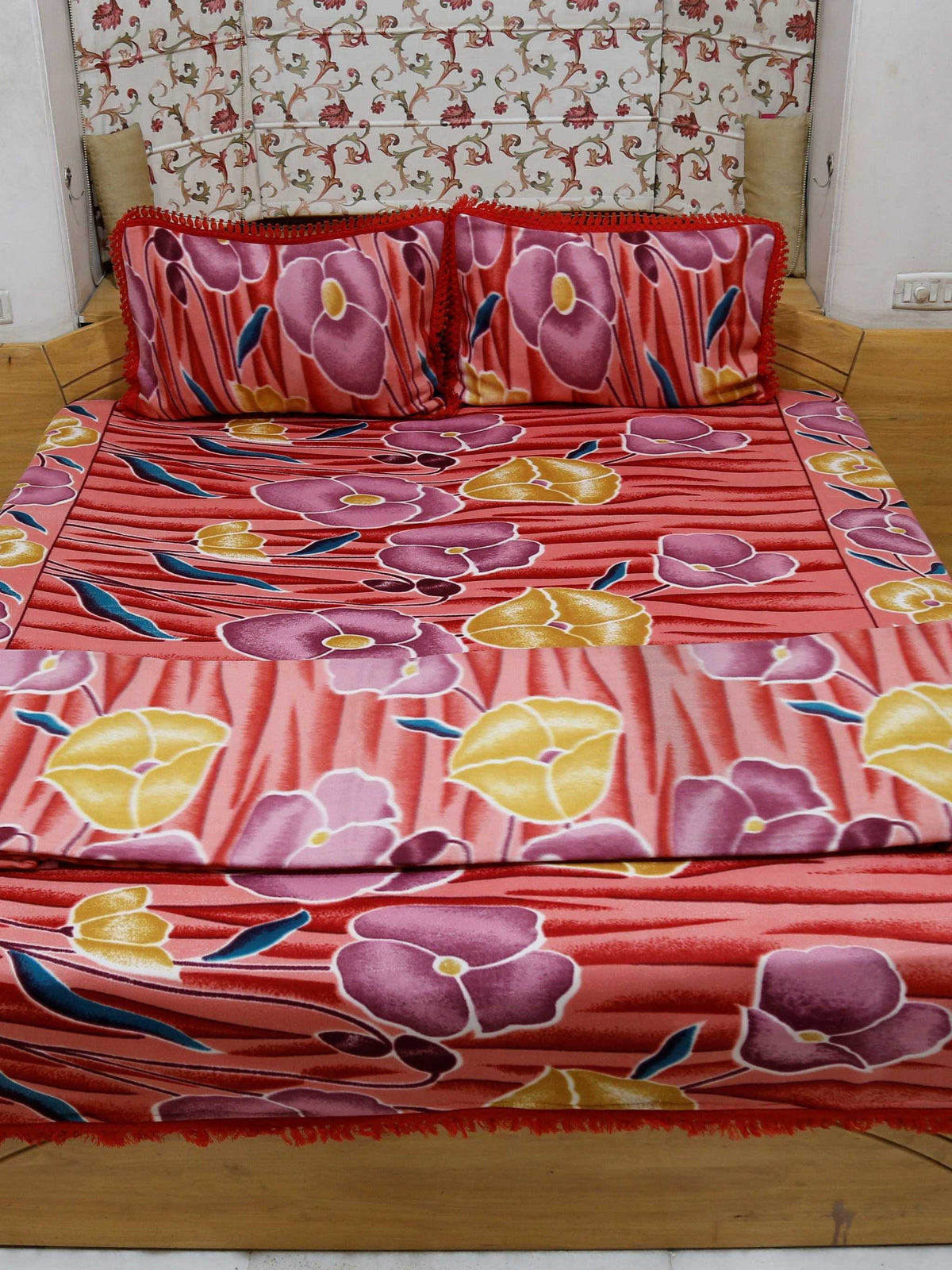 Coral-red blanket set with a mauve-purple and mustard-yellow poppy floral print, folded on a bed with matching pillow covers