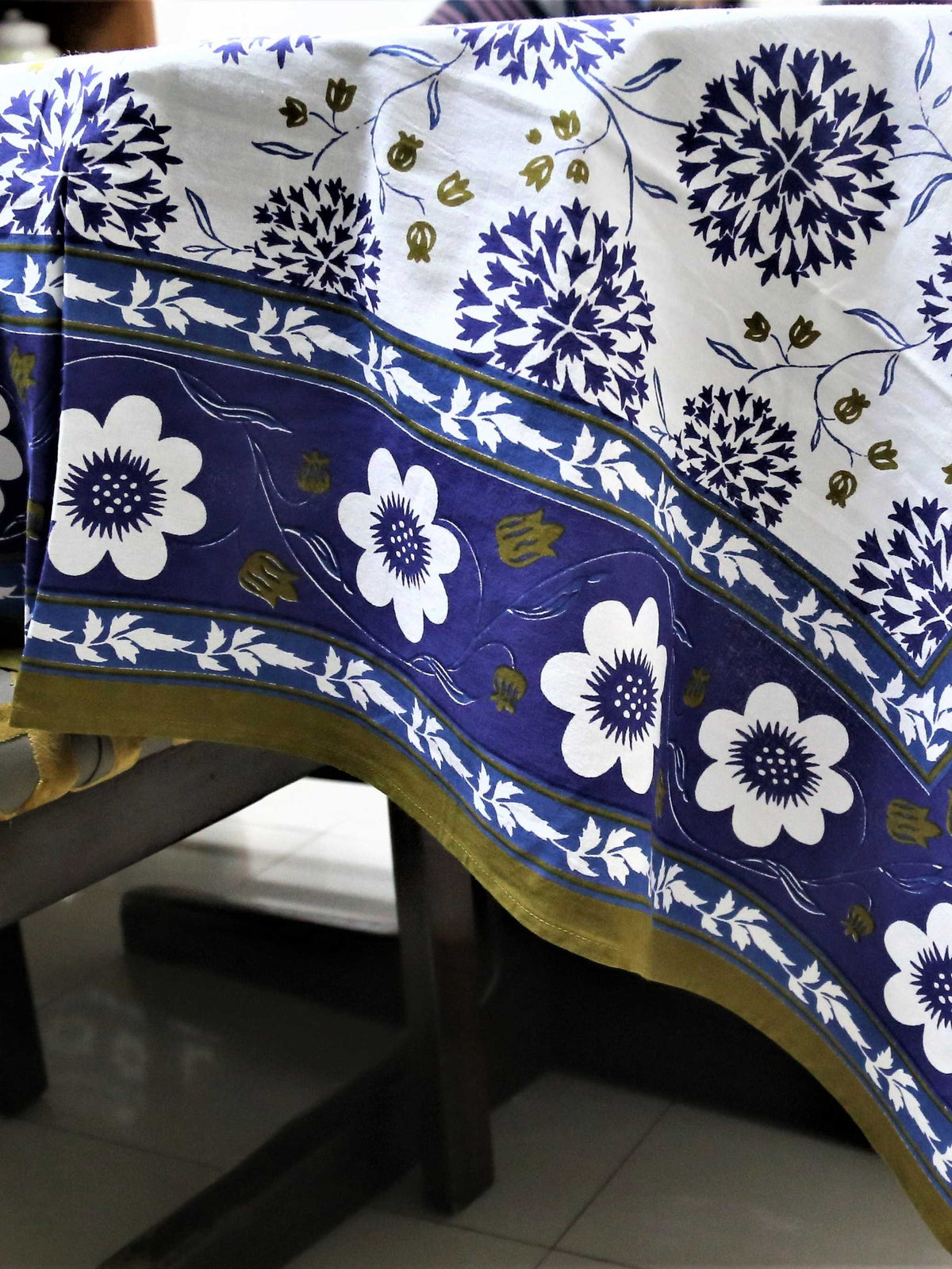 White oval table cover with a navy-blue dahlia and pompom floral print and a navy border with white flowers