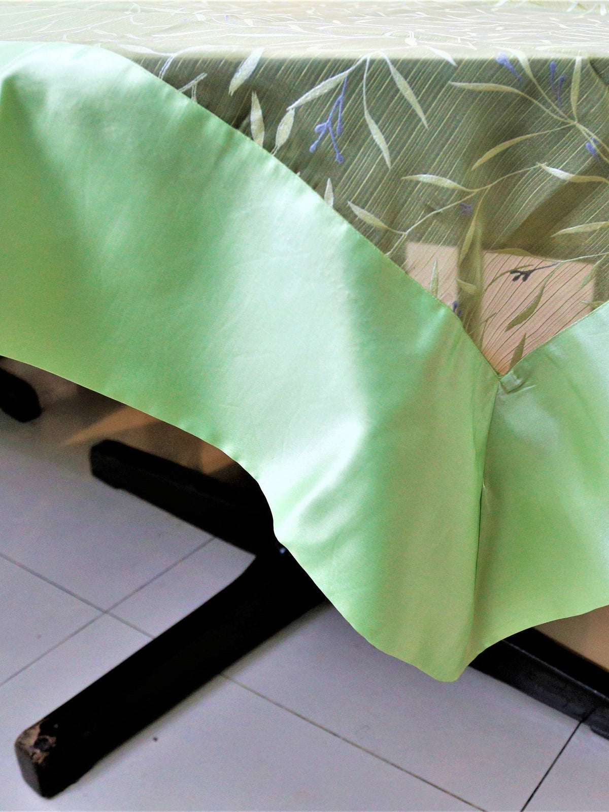 Olive-green table cover with a white and silver embroidered leaf-and-vine pattern and a pale mint-green satin border