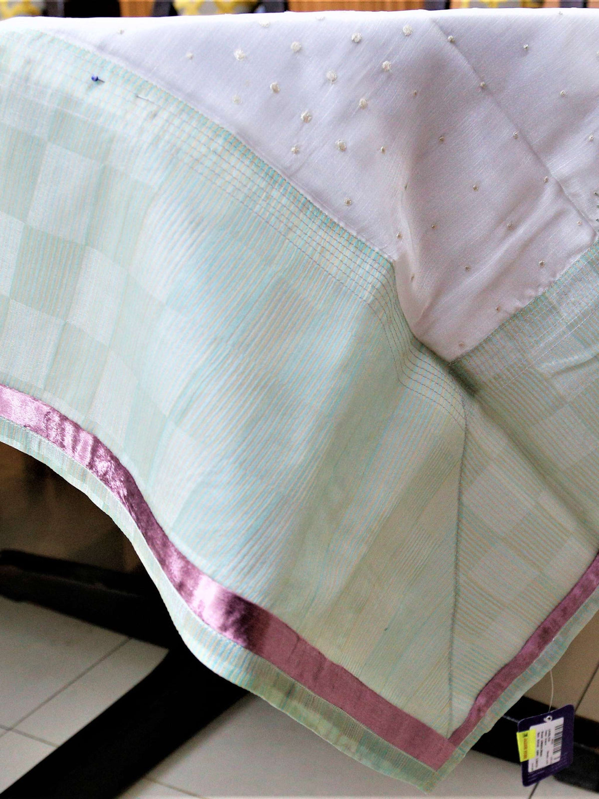 White table cover with lavender embroidered wheat-sprig motifs and scattered gold dots, with a mint-green checkered underskirt trimmed in pink