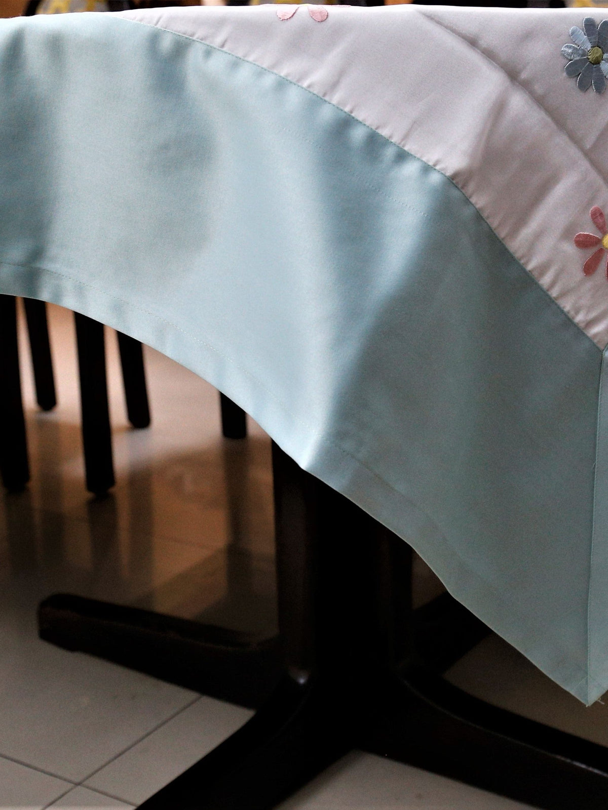 White table cover with a sequinned multicolour daisy dot pattern and a solid sea-green satin border
