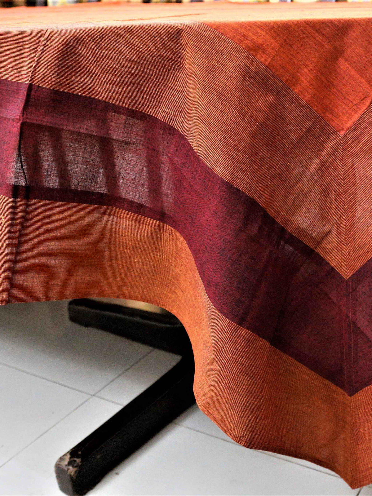 Solid rust-orange table cover with a maroon and rust horizontal striped border