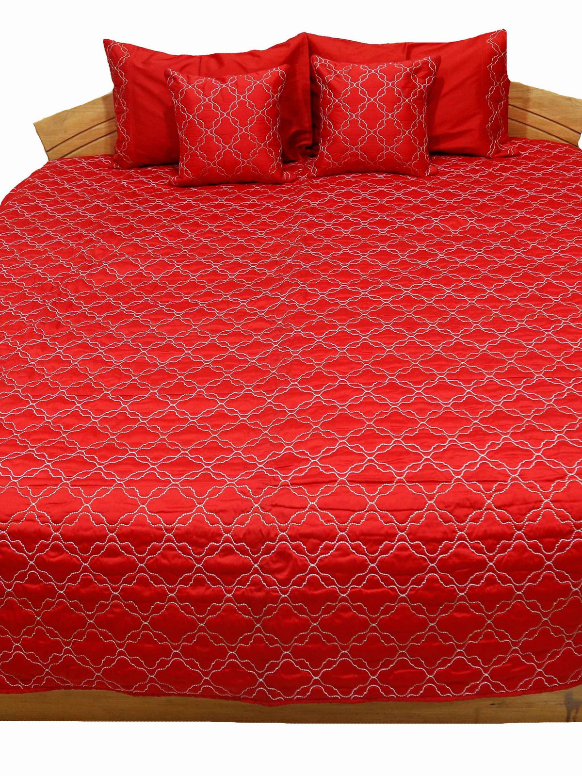 Red quilted double bedcover with a white diamond-lattice embroidery, angled view showing the matching pillow and cushion covers