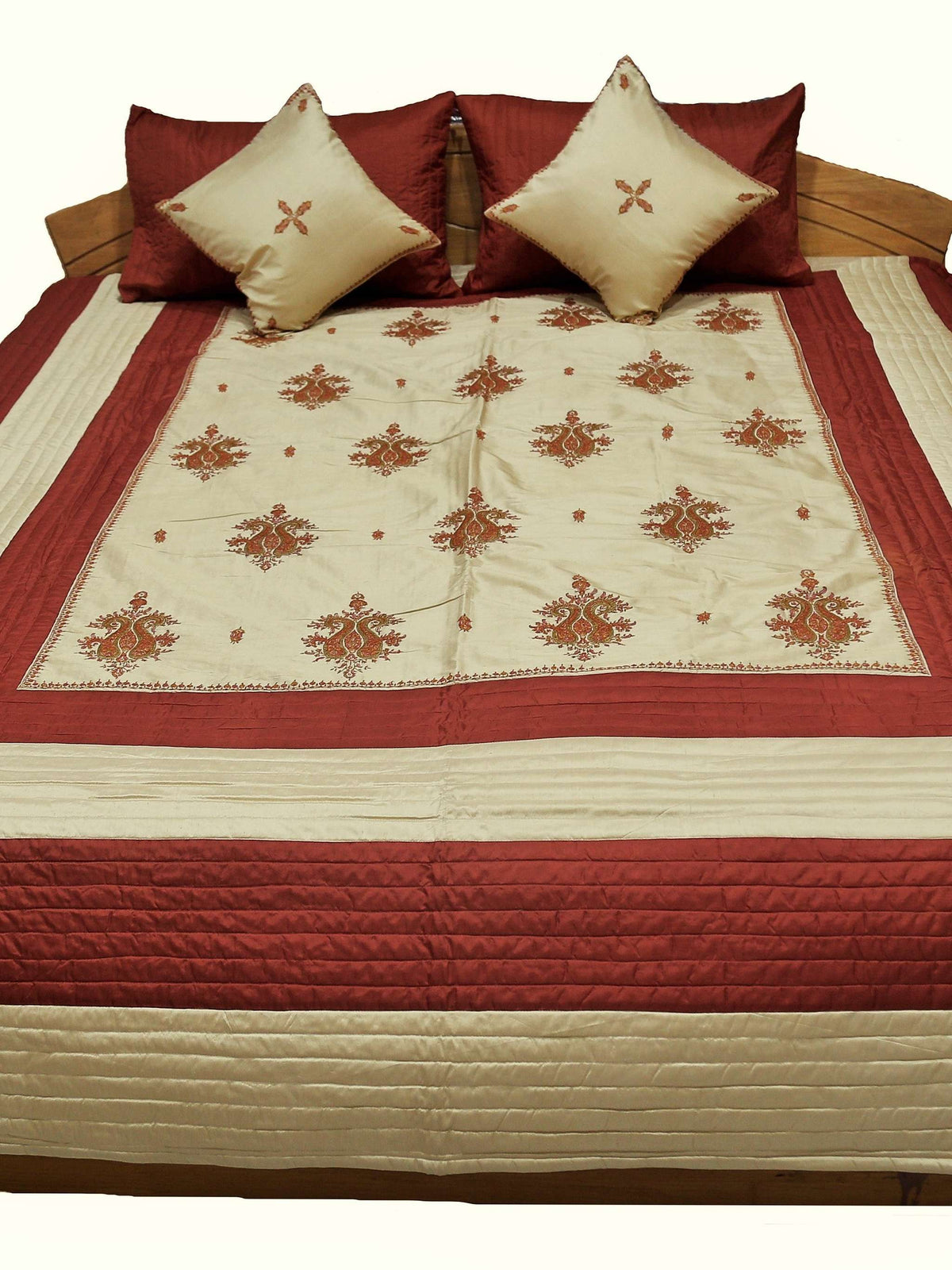 Maroon and cream double bedcover with a floral-embroidered border, angled view on the bed
