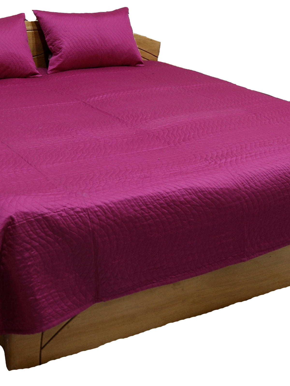 Magenta side of the reversible quilted bedcover with two pillow covers, angled view