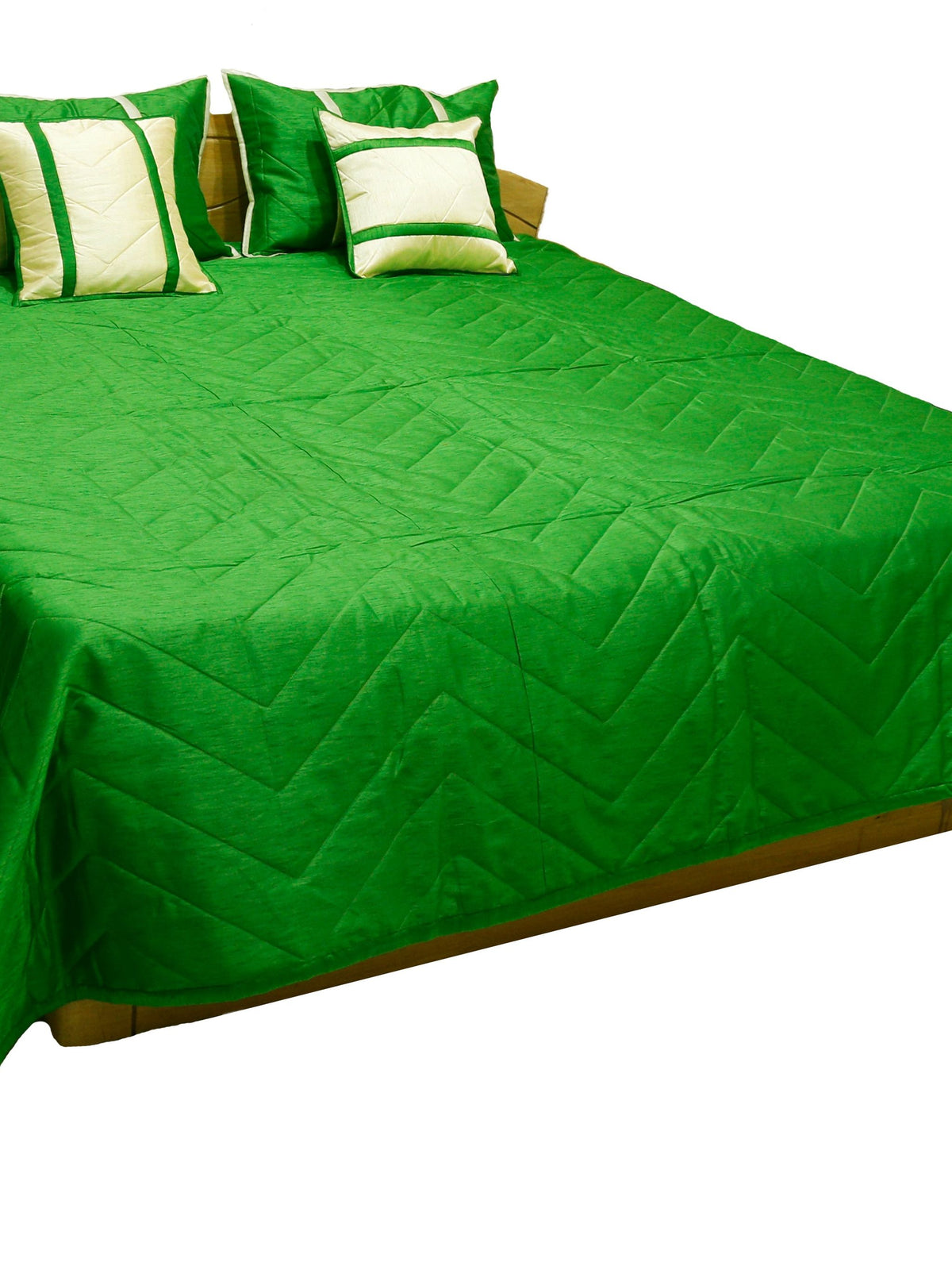 Emerald green quilted bedcover with cream banded cushion covers, angled view