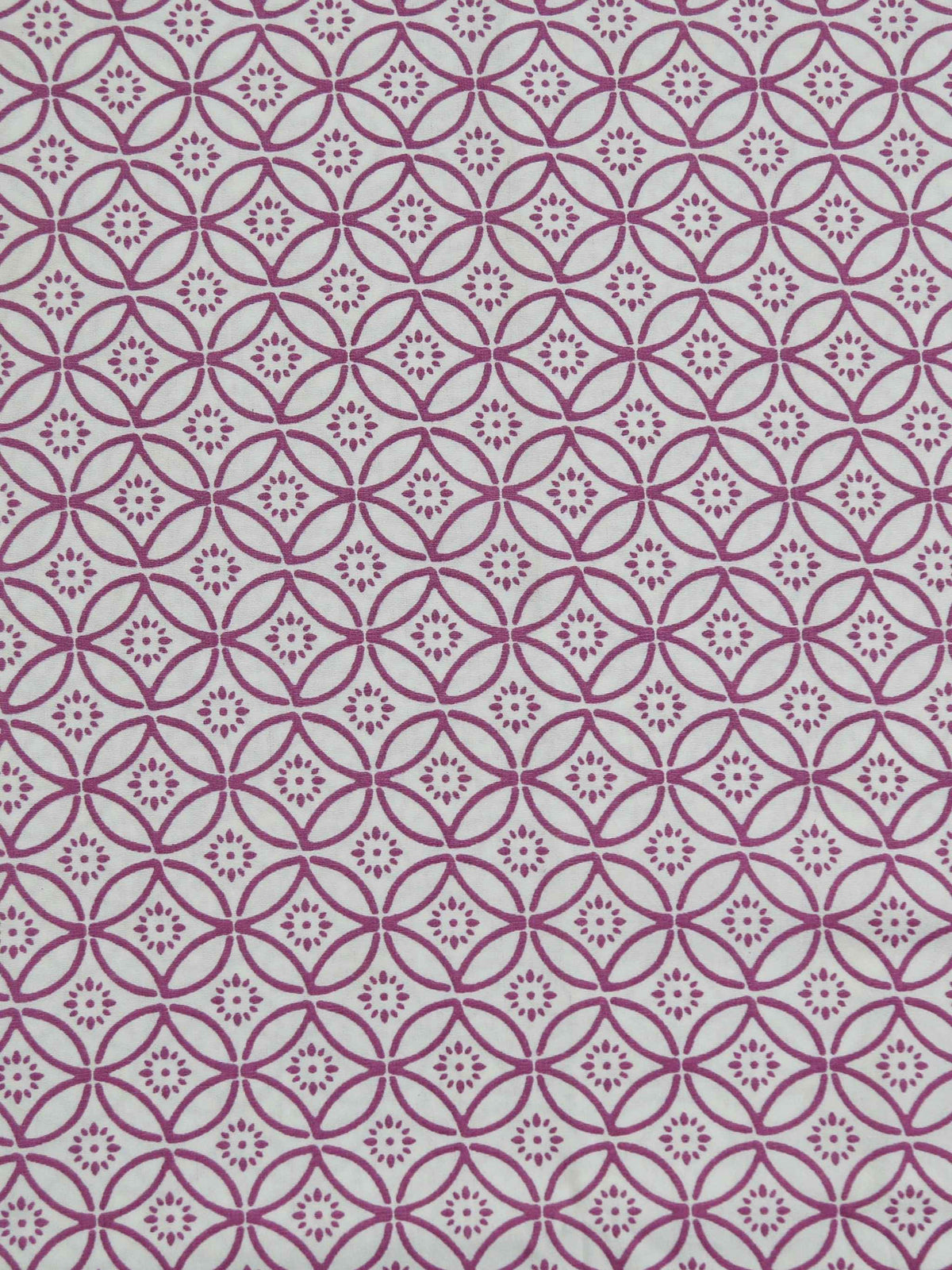 Close-up of magenta quatrefoil-circle geometric print fabric on a white cotton bedsheet
