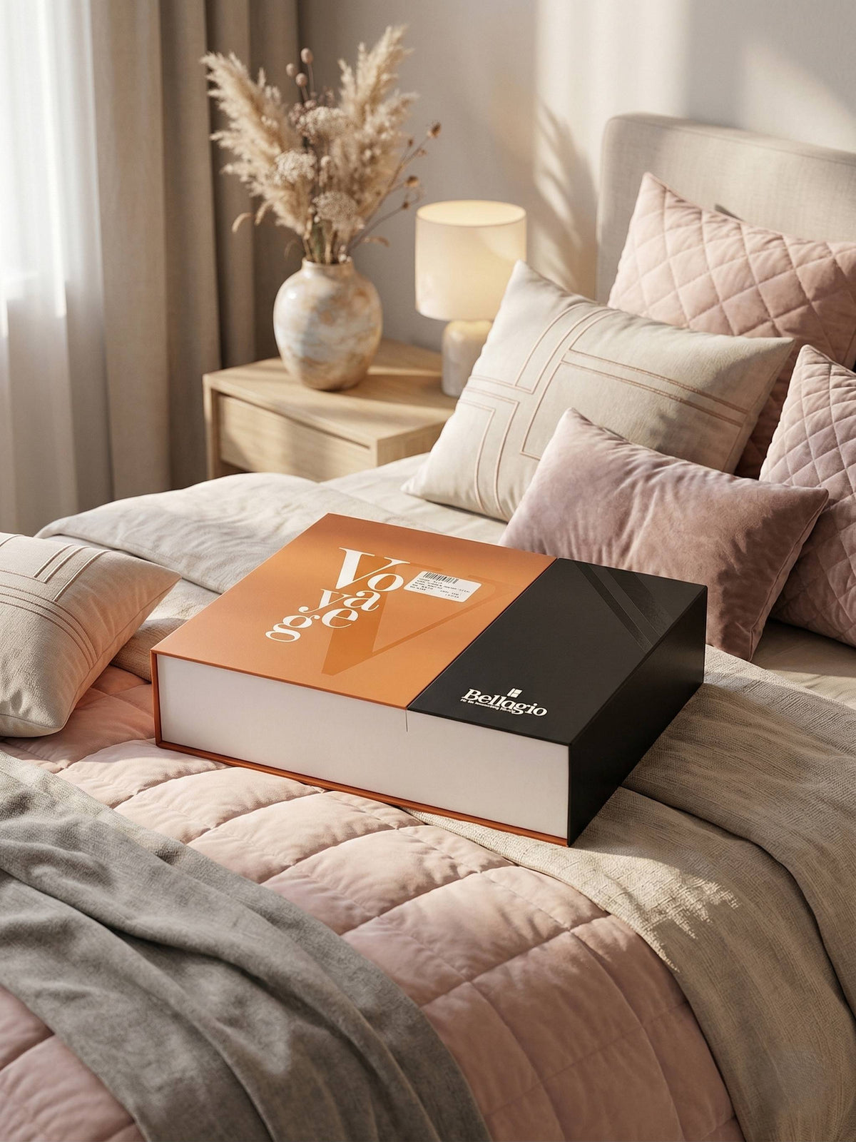 Closed Voyage gift box on a bed dressed in blush and grey bedding