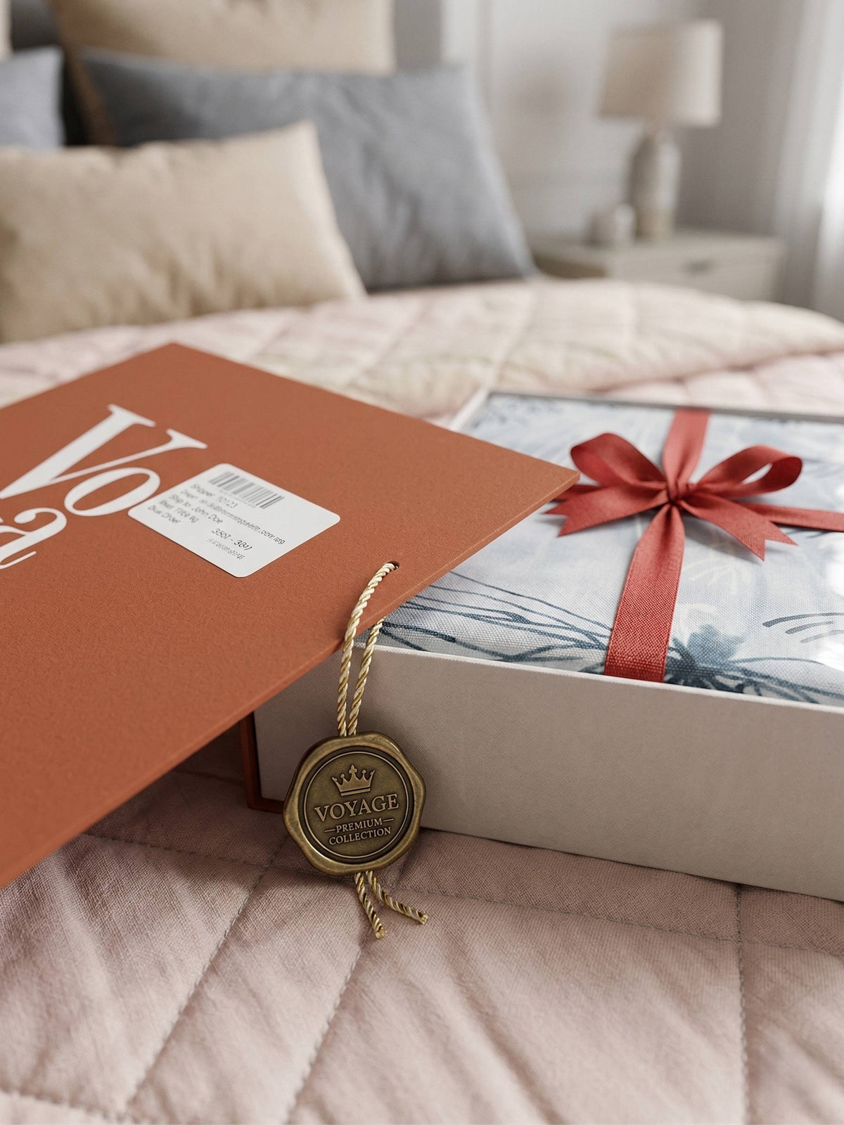 Voyage gift box open on a bed, the sheet tied with a red ribbon and a key charm tag